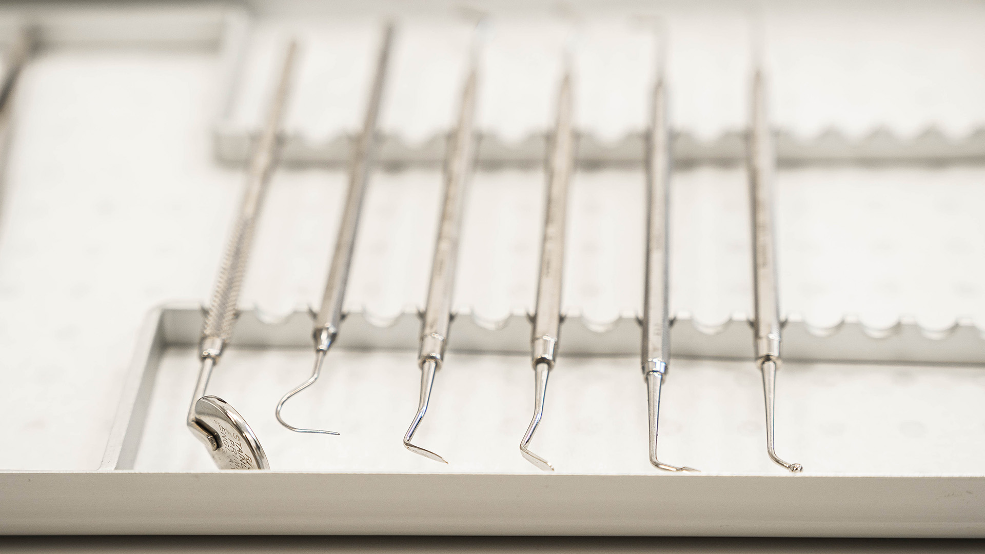 Dentists tools lined up on a tray.